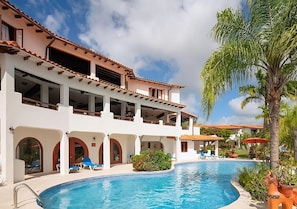 A two-story building with a swimming pool, outdoor seating, and palm trees. - Scenic Maynards Stay | Farley Hill National Park - 4 Miles | 3 Suites (Maynards)