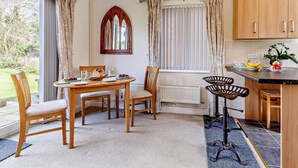Ein Essbereich mit Tisch und Stühlen, eine Küche mit Holzschränken und ein Fenster mit Vorhängen.