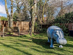 A garden with a wooden bench, a large blue hippo sculpture, and a wooden fence. - 1 Bed in North Walsham (oc-82143) (North Walsham)