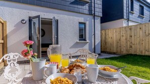 Une table dressée pour le petit-déjeuner, avec des chaises et une variété d’aliments et de boissons.