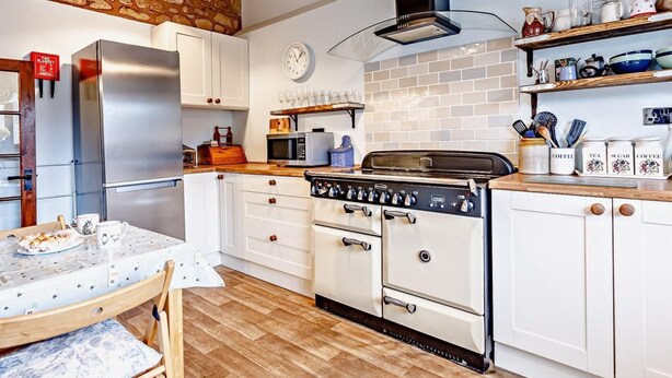 A kitchen with white cabinets, a stainless steel refrigerator, a gas stove, and a clock on the wall. - 1 Bed in Watchet (oc-81240) (Washford)