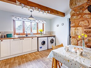 Eine Küche mit Holzausstattung, einer Waschmaschine, einem Tisch mit Tischdecke und einer Steinwand.