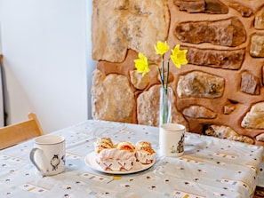 A table with a plate of pastries, a mug, and a vase with flowers. - 1 Bed in Watchet (oc-81240) (Washford)