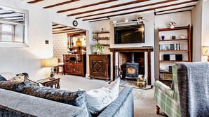 A living room with exposed wooden beams, a fireplace, a television, and a bookshelf. - 1 Bed in Watchet (oc-81240) (Washford)