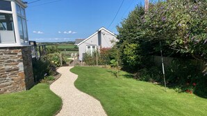 A well-maintained garden with a gravel path leading to a house. - 1 Bed in Bude (oc-82365) (Jacobstow)