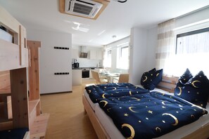 Un dormitorio moderno con literas, una kitchenette y un comedor.