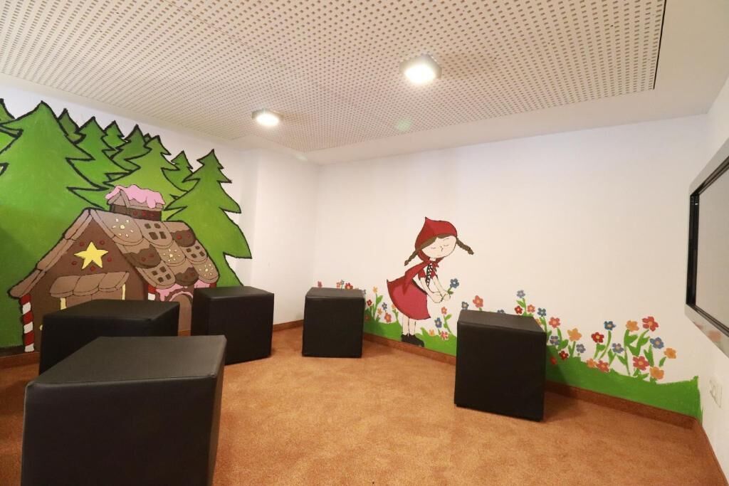 A room with a white ceiling, green wall mural, and a projector screen.
