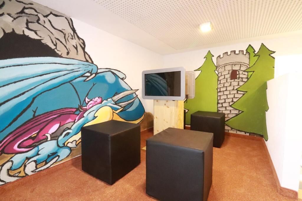 A room with a large mural, a television, and a castle-themed wall decoration.