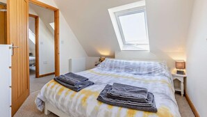 A bedroom with a sloped ceiling, a skylight, a bed with towels, a bedside table with a lamp, and a wardrobe. - 2 Bed in Bude (oc-82163) (Bude)