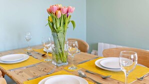 A dining table set with plates, cutlery, and wine glasses, with a vase of flowers in the center. - 2 Bed in Bude (oc-82163) (Bude)