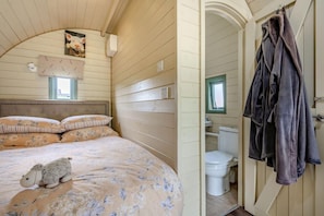 A bedroom with a bed, a headboard, a window, and a wall-mounted picture.