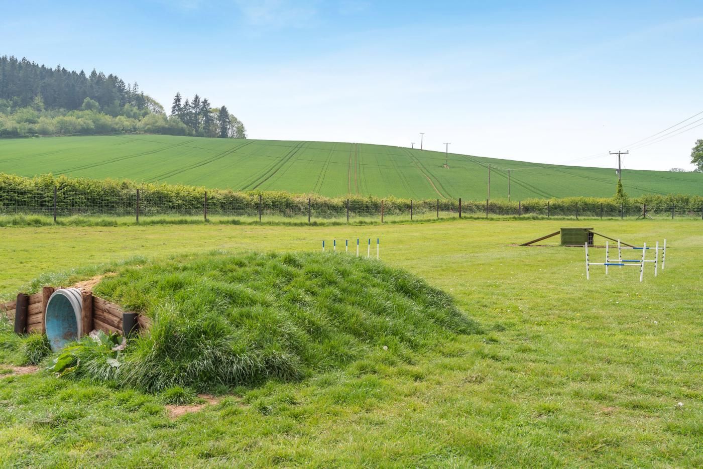 Un paysage rural avec un champ, une construction en bois et une clôture.