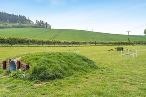 A rural landscape with a field, a wooden structure, and a fence.