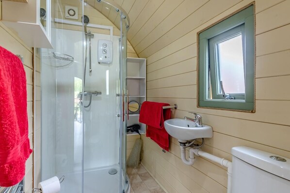 A bathroom with a glass-enclosed shower, a white sink, and a window with a green frame.