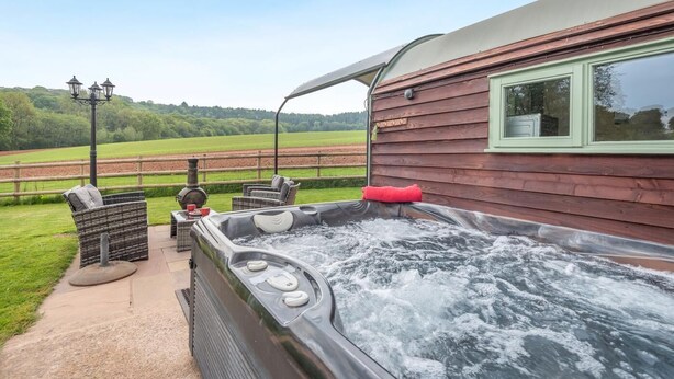 A hot tub with a view of a green field, a wooden building, and outdoor furniture. - 1 Bed in Hereford (oc-81292) (Aconbury)