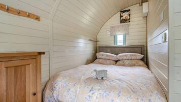 Une chambre avec un lit superposé en bois, une armoire en bois, une petite fenêtre et un luminaire fixé au mur.