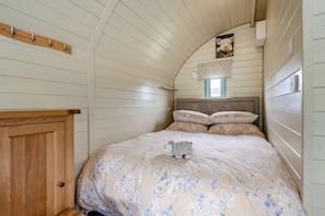 A bedroom with a wooden bunk bed, a wooden wardrobe, a small window, and a wall-mounted light fixture.