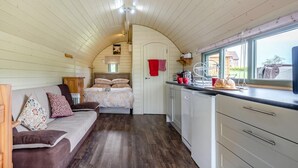 A cozy interior with a bed, a sofa, a kitchen area with a window, and wooden walls. - 1 Bed in Hereford (oc-81292) (Aconbury)