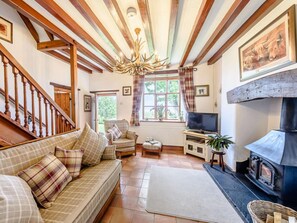 Ein gemütliches Wohnzimmer mit einer Couch, Fernseher, Kamin und Holzbalken an der Decke.