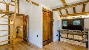 A room with exposed wooden beams, a wooden ladder, a television, and wooden wine boxes. - 1 Bed in Ashford (oc-82527) (Biddenden)