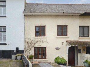 A two-story building with a white exterior, a small front porch, and a door with a sign that reads 'Stone Barn Cottage.' - 4 Bed in Brixham (oc-82519) (Brixham)