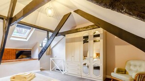 Un dormitorio con cama, armario, silla y tragaluz.