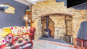 Una sala acogedora con chimenea de piedra, sofá de cuero y estantería.
