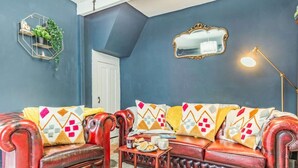 Una sala de estar con un sofá de cuero rojo, una mesita de centro, un espejo y una lámpara.