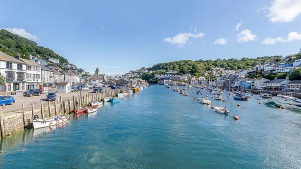Un puerto con barcos amarrados a lo largo de la costa, edificios a ambos lados de las calles y un cielo azul despejado.