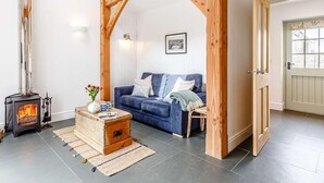 Een gezellige woonkamer met een blauwe bank, een houten open haard en een landelijke deur.