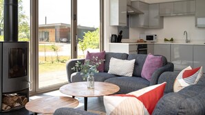 Een moderne woonkamer met een bank, salontafel en een houtkachel.