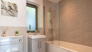 Een moderne badkamer met douche, toilet en wastafel.