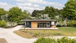Een modern huis met een terras, een jacuzzi en een oprit naar de ingang.