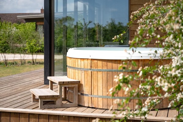 A wooden deck with a hot tub and a bench.