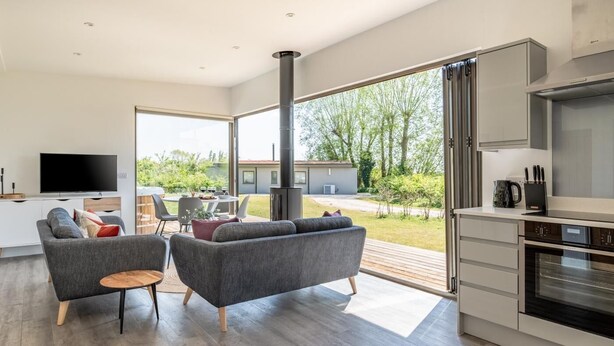Een moderne woonkamer met een televisie, twee banken, een salontafel en een keuken met een fornuis.