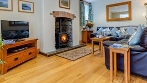 Una sala de estar acogedora con chimenea de piedra, televisor, sofá y mesa de centro.