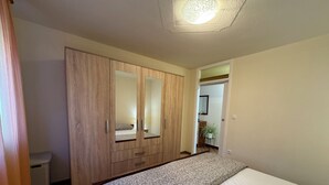 Ein Schlafzimmer mit Bett, Holzschrank und Deckenleuchte.