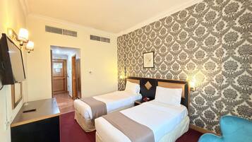Une chambre d’hôtel avec deux lits, une télévision et un papier peint à motifs.