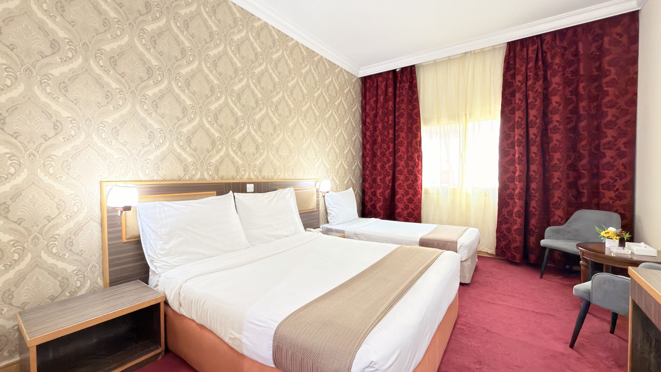 Een hotelkamer met twee bedden, een bureau en een stoel.