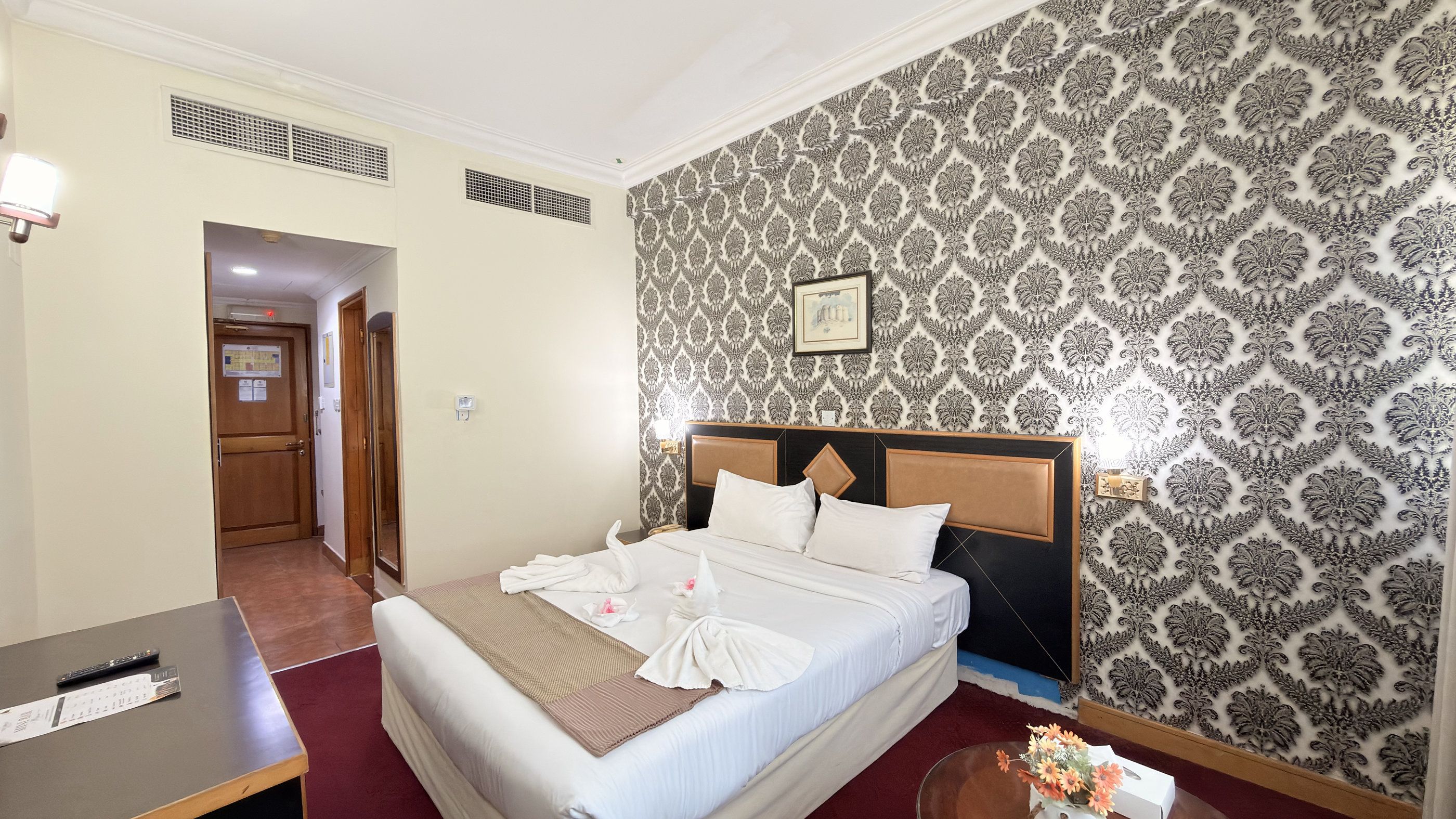 Een hotelkamer met een bed, een bureau en een muur met behang.