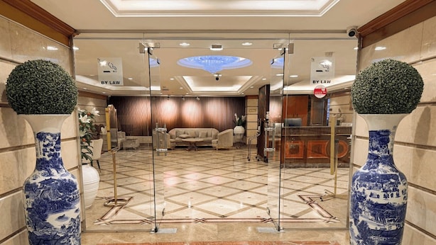 A lobby with a checkered floor, two large vases, a reception desk, and a sofa. - Elite Jonrad Hotel (Dubai)