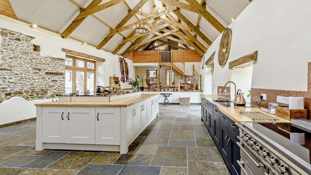 A spacious kitchen with a large island, stone walls, and a high wooden ceiling. - 6 Bed in Torrington (oc-81519) (Great Torrington)