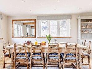 A dining room with a large table, wooden chairs with cushions, a mirror, and a window with curtains. - 4 Bed in Tiverton (oc-82433) (Witheridge)