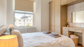 A bedroom with a bed, a window, a dresser, and a lamp. - 2 Bed in Tenby (oc-82226) (Tenby)