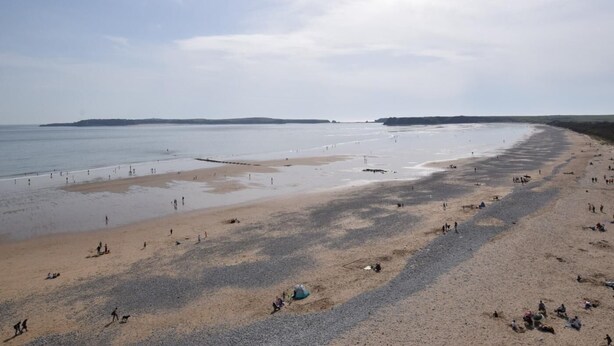 A wide beach with people walking and sitting, a calm sea, and a clear sky. - 2 Bed in Tenby (oc-82226) (Tenby)