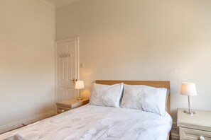 A standard hotel room with a single bed, a nightstand, a bedside table, and a door. - 2 Bed in Tenby (oc-82226) (Tenby)