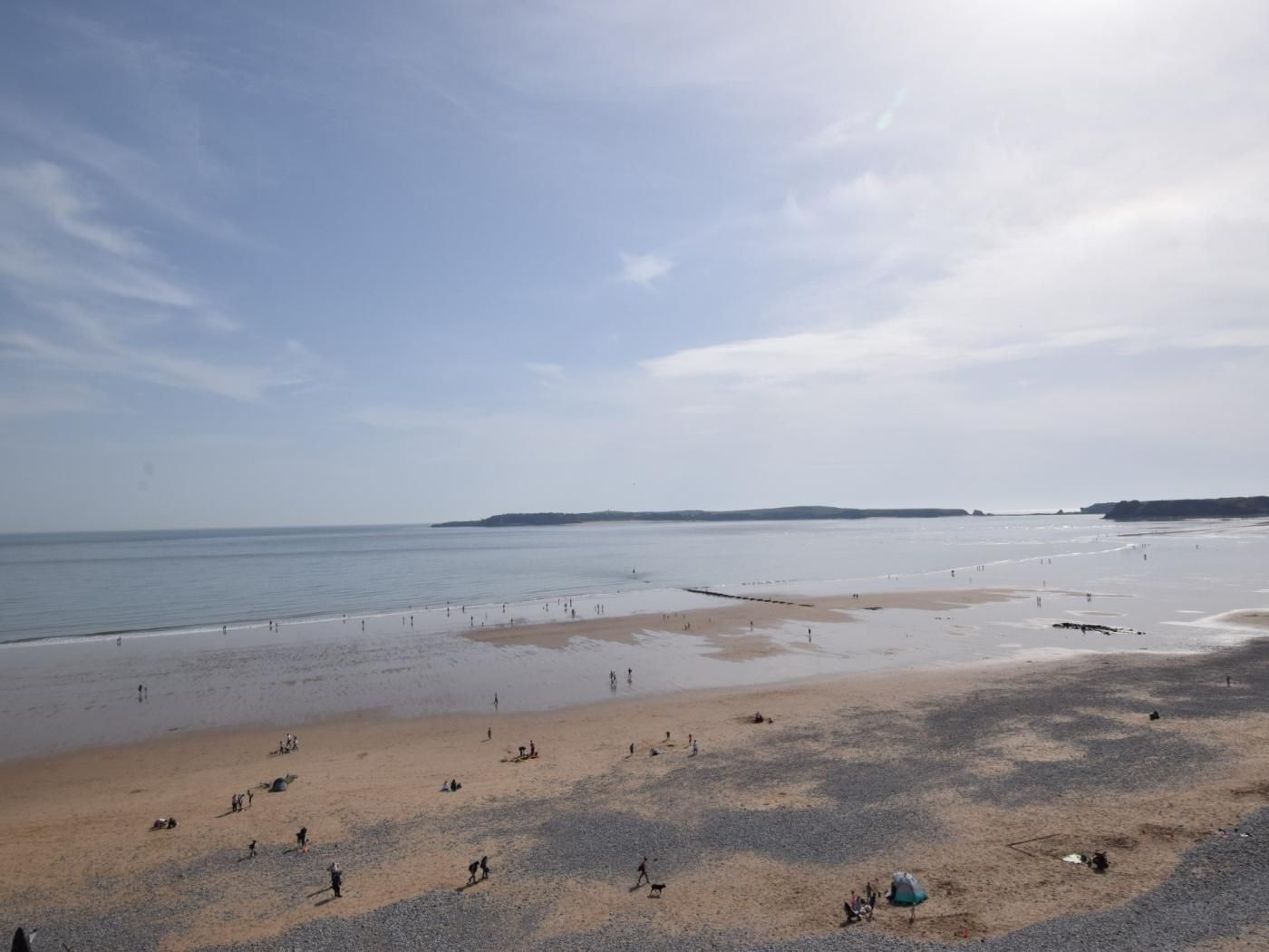 Una spiaggia ampia con persone sparse sulla sabbia e in acqua.