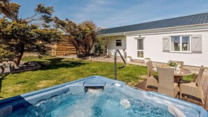 En trädgård med en bubbelpool, ett hus och en träterrass.