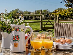 A wicker table with a pitcher, glasses, and plates of food. - 2 Bed in Holyhead (oc-81515) (Caergeiliog)
