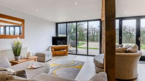 A modern living room with a large window, a flat-screen TV, and a cozy seating area. - 2 Bed in Ipswich (oc-81441) (Witnesham)